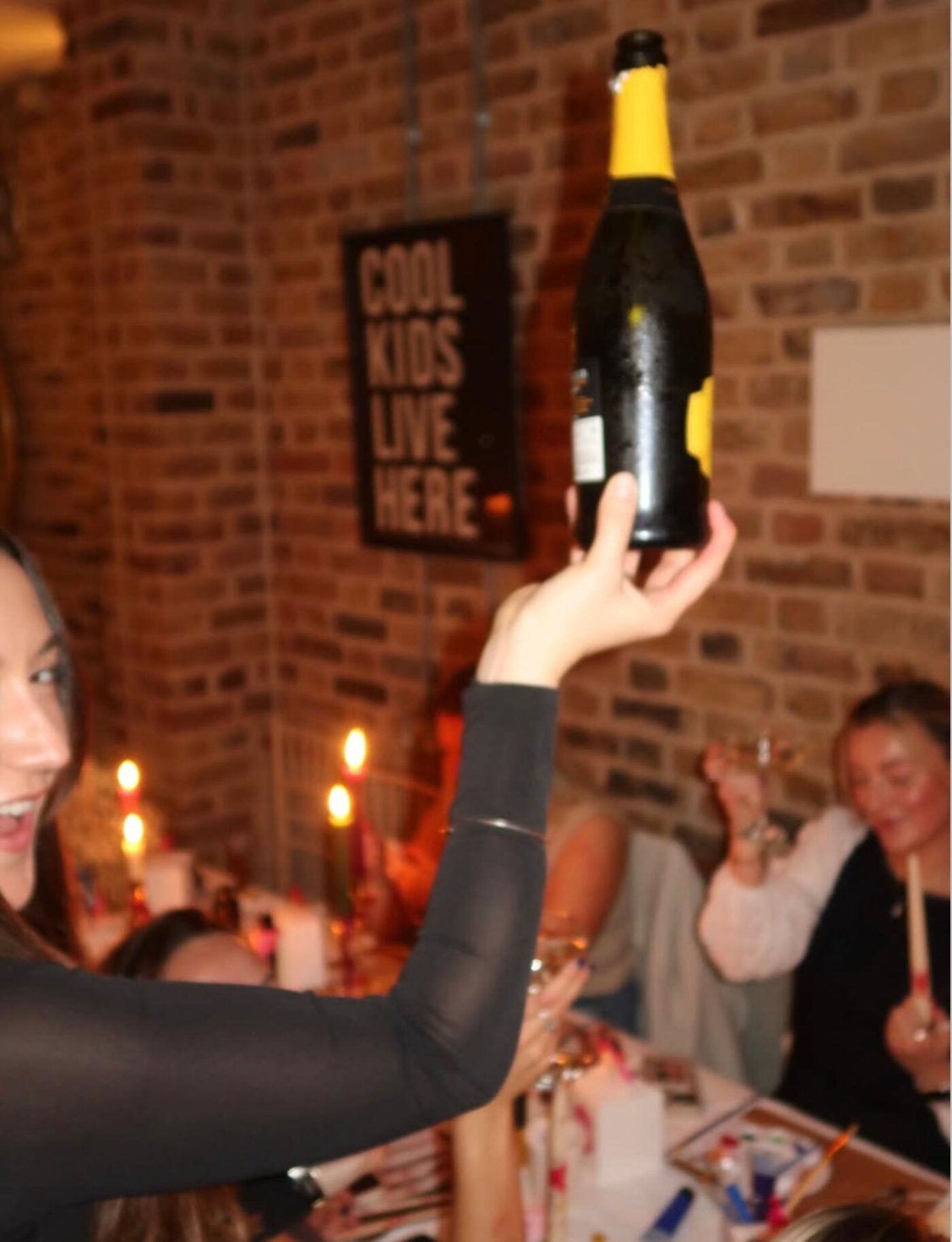 Guest holding a bottle of fizz up in the air