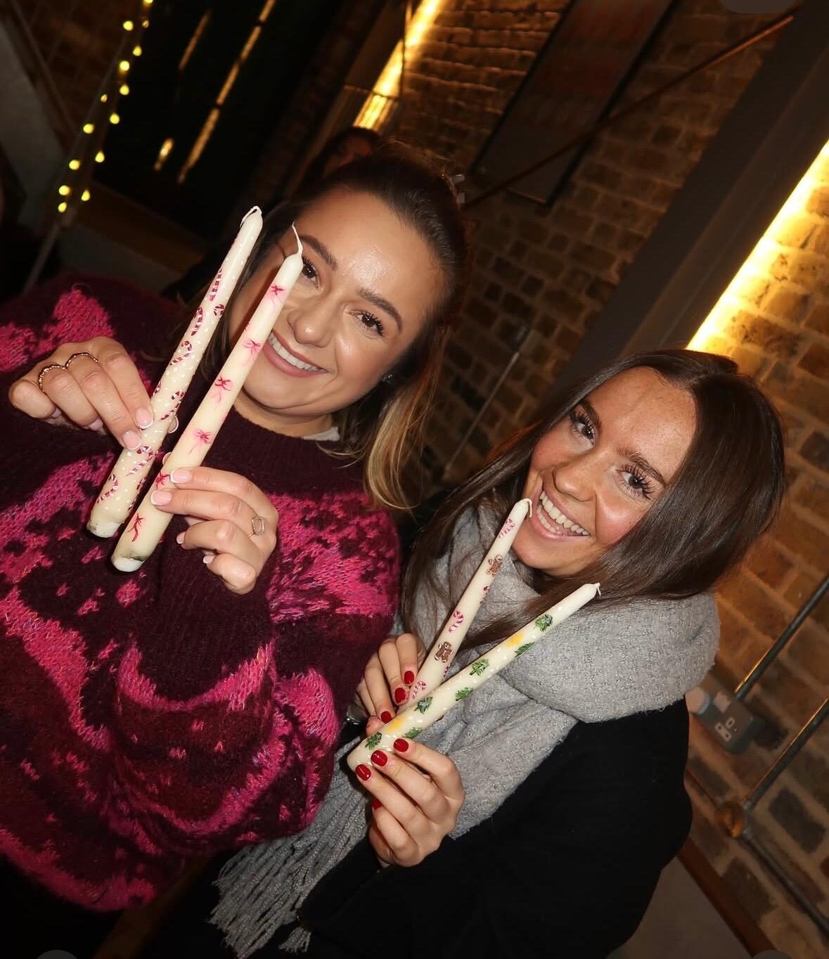 Two guests holding up their hand painted Christmas candles